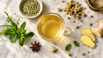 Herbal debloat tea in a glass cup with fennel seeds, fresh mint and ginger