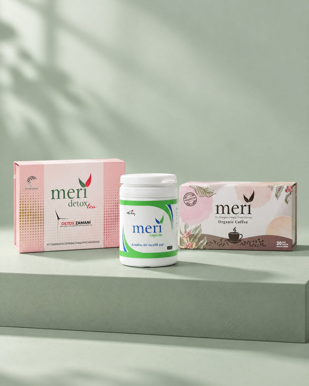 Cápsulas, té y café detox colocados lado a lado sobre un pedestal verde salvia