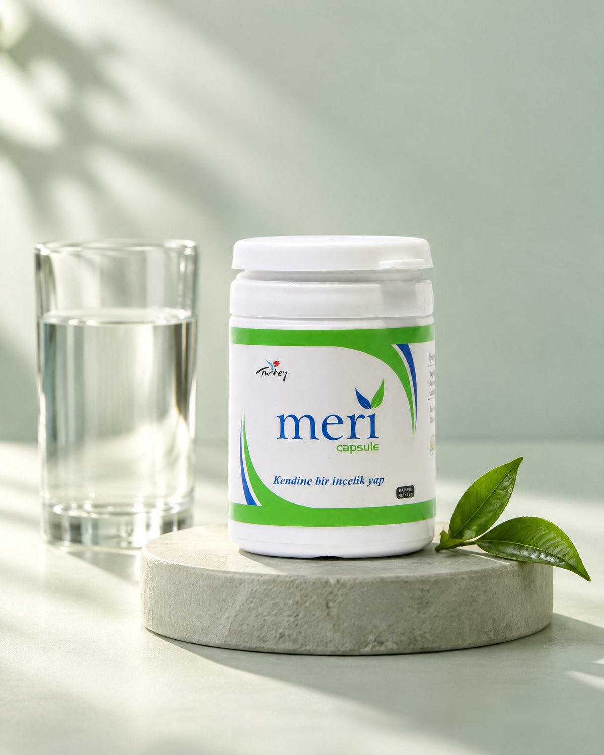 Detox capsule tub on a sage plinth beside a glass of water